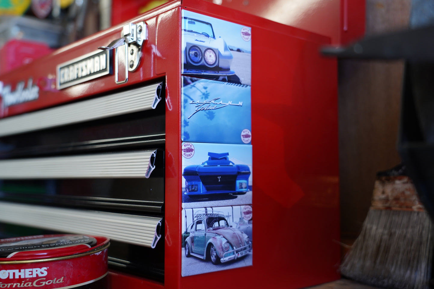 Red toolbox with a screen displaying images of cars, surrounded by various items in a workshop setting.