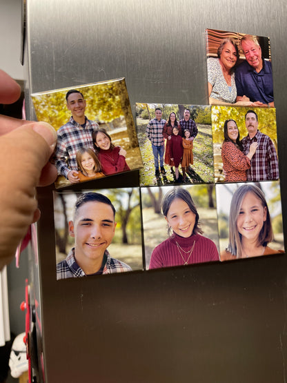Hand placing custom 2x2 square magnet on fridge surface